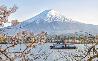 A view towards Mount Fuji with a boat on Lake Kawaguchiko, and cherry blossom